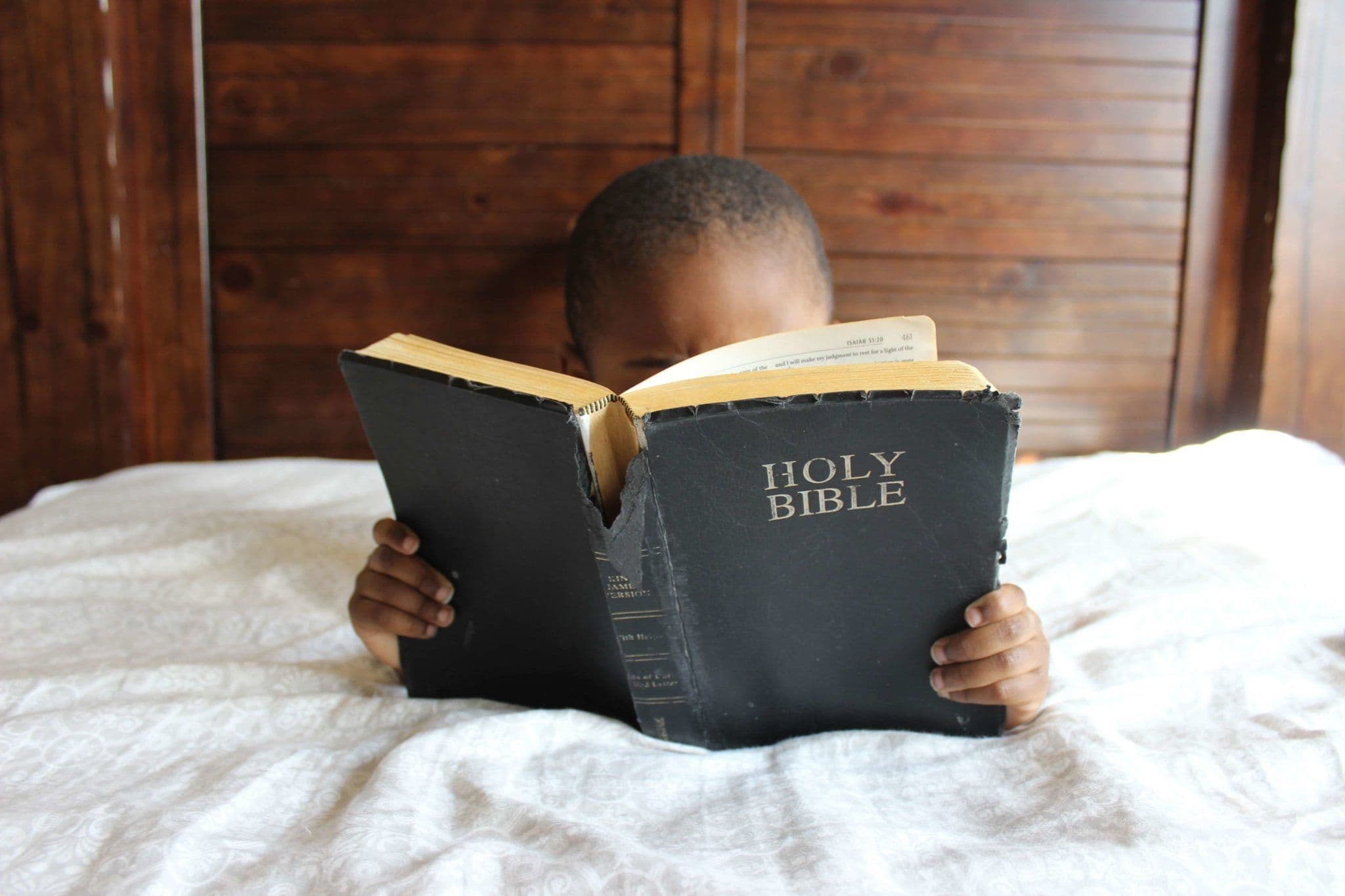 Mtoto akisoma Biblia akiwa kitandani